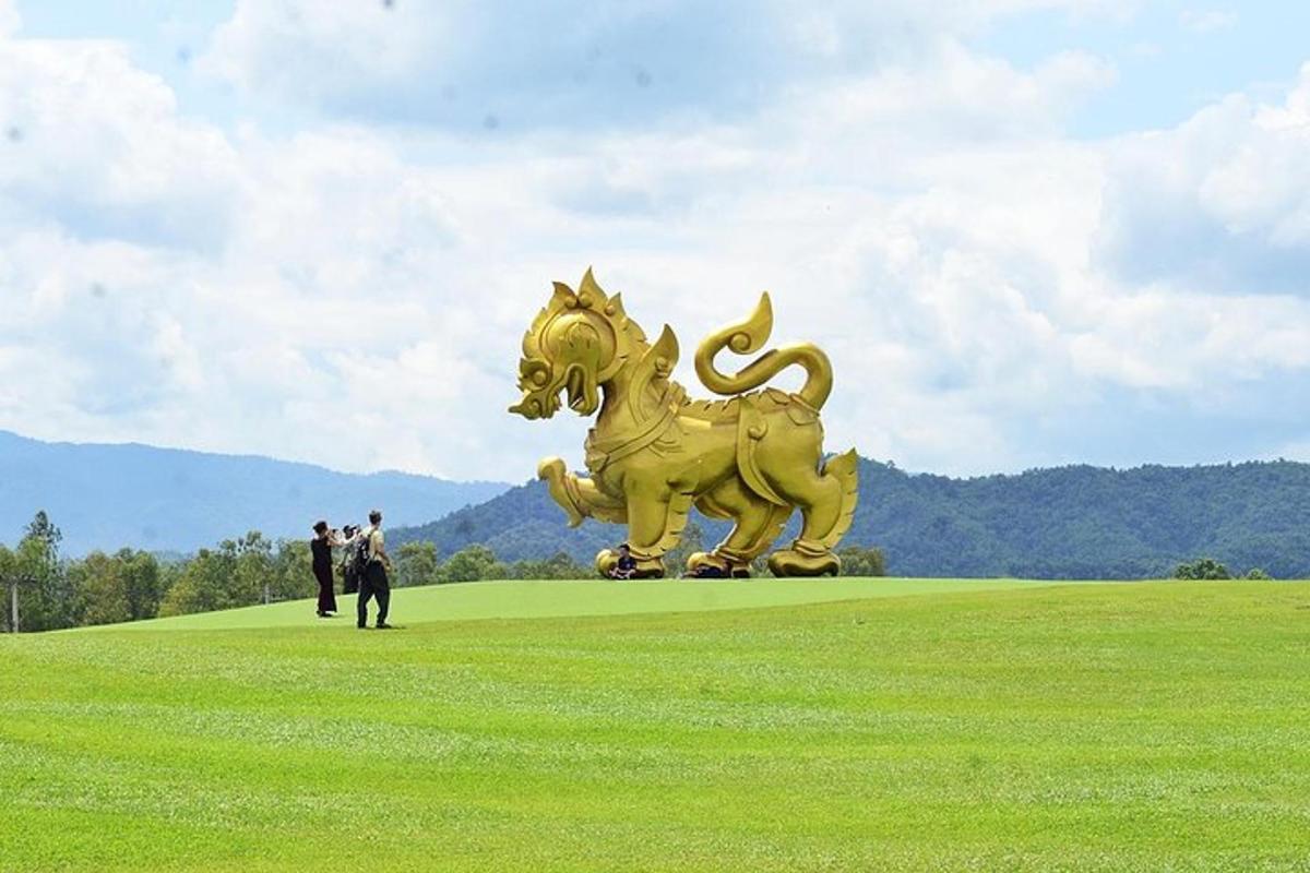 two people standing in front of a large gold dragon statue