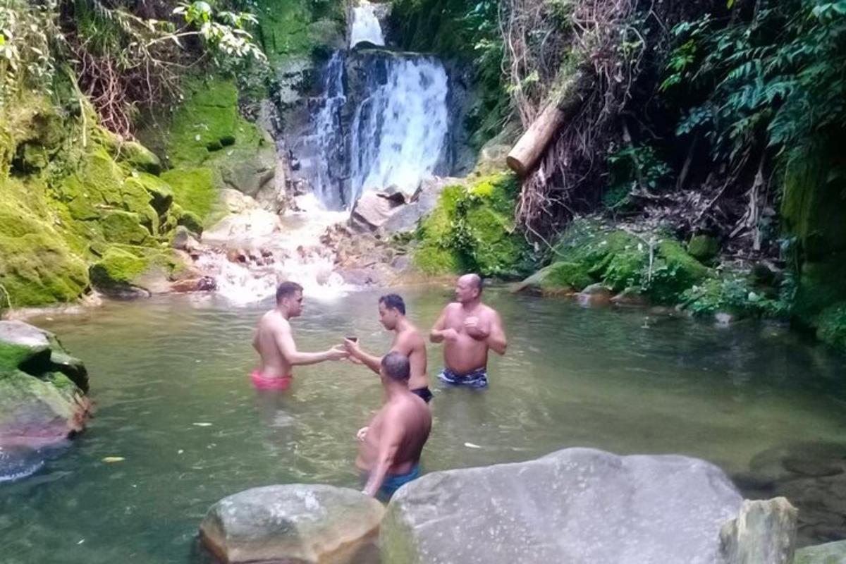 quatro homens na água perto de uma cachoeira