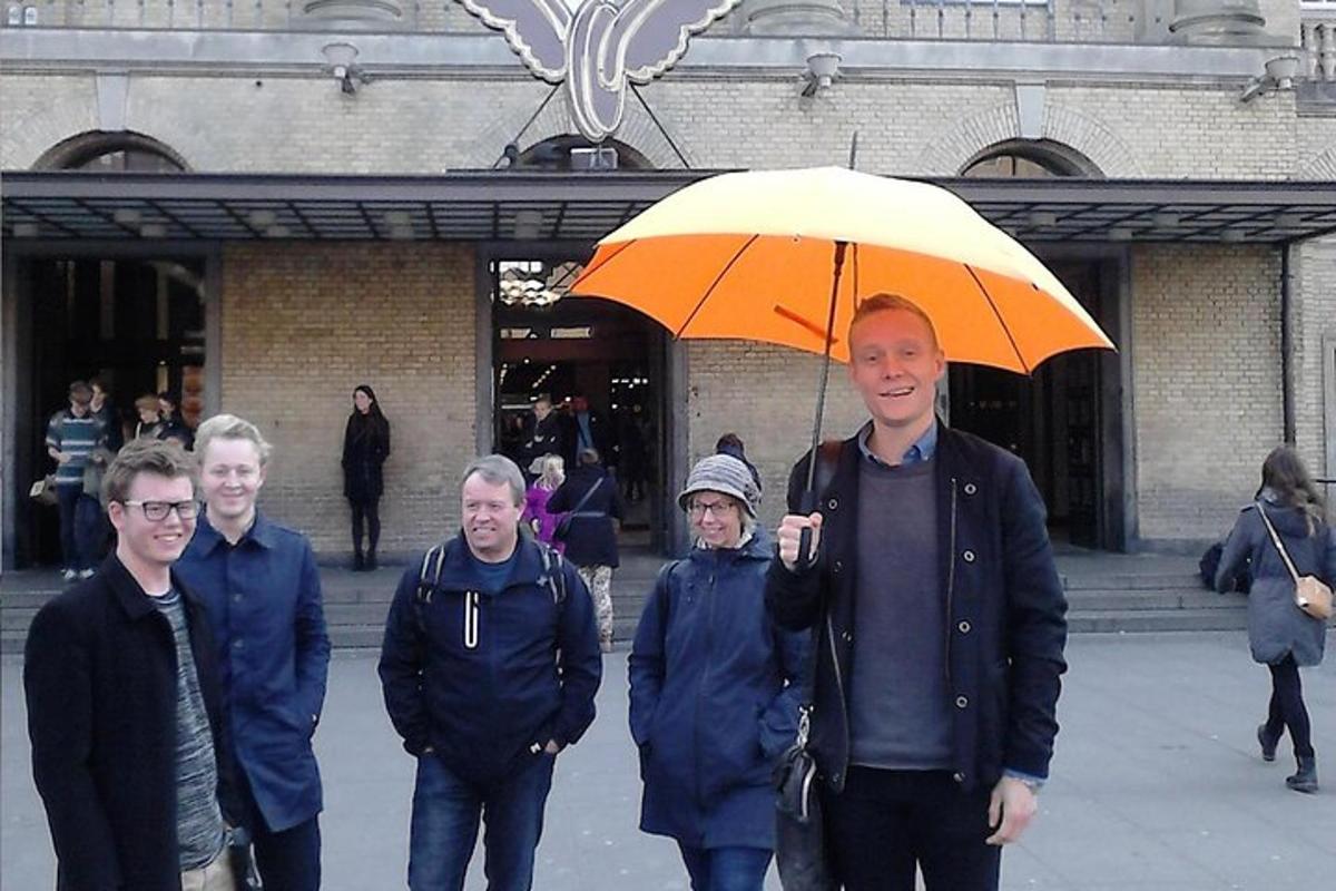 a man holding an orange umbrella next to a group of people