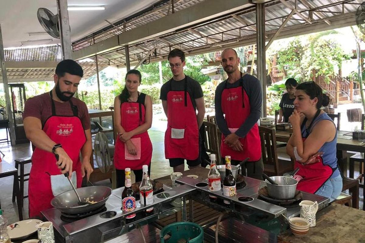 Un grupo de personas con delantales rojos en una cocina.