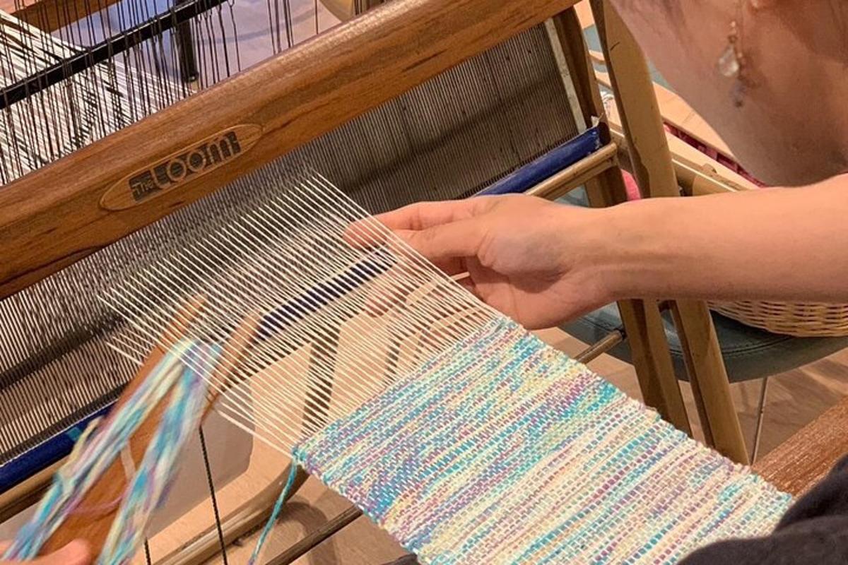 a person is holding a weaving instrument on a loom