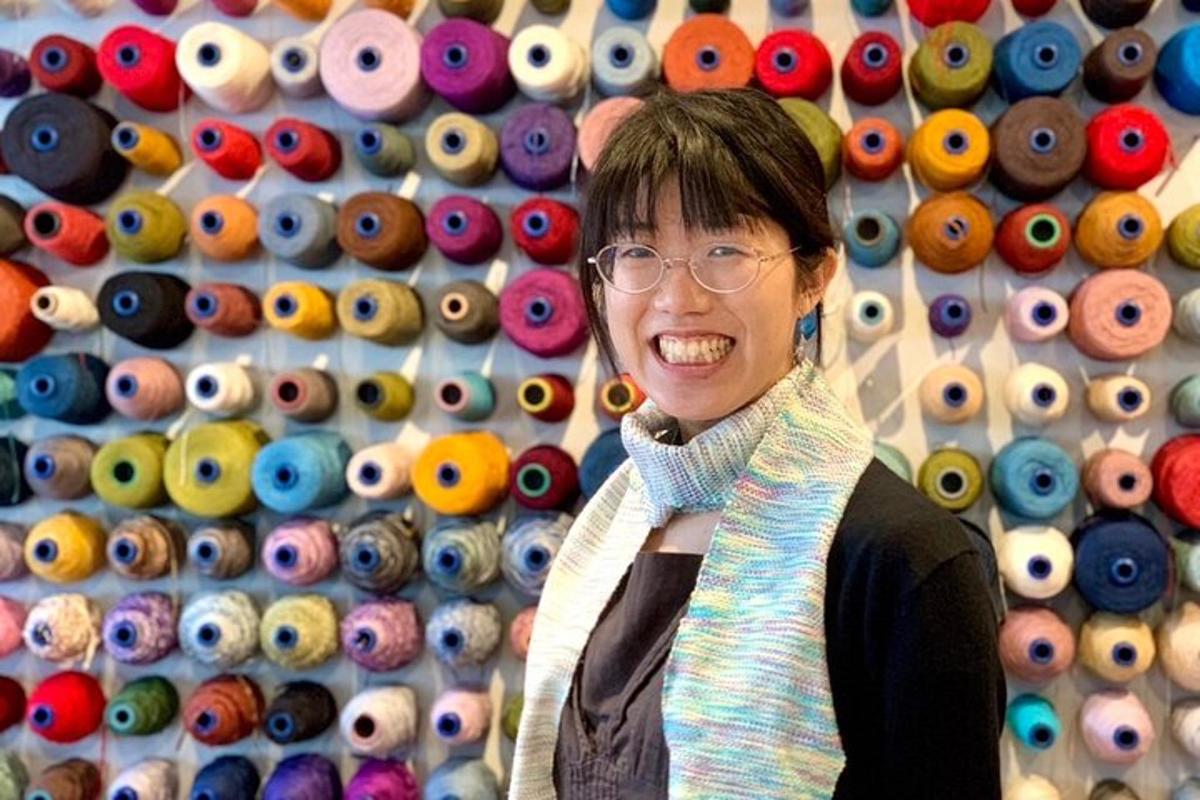 a woman is standing in front of a wall of eyes