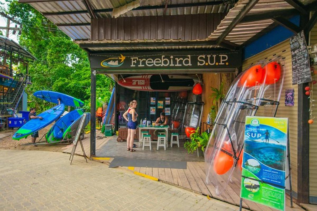 una donna in piedi davanti a un negozio di pesce con tavole da surf