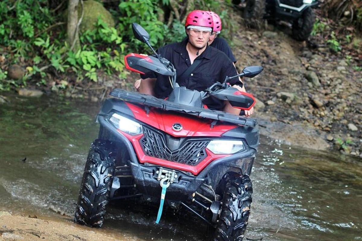 a man riding a four wheeler through a river