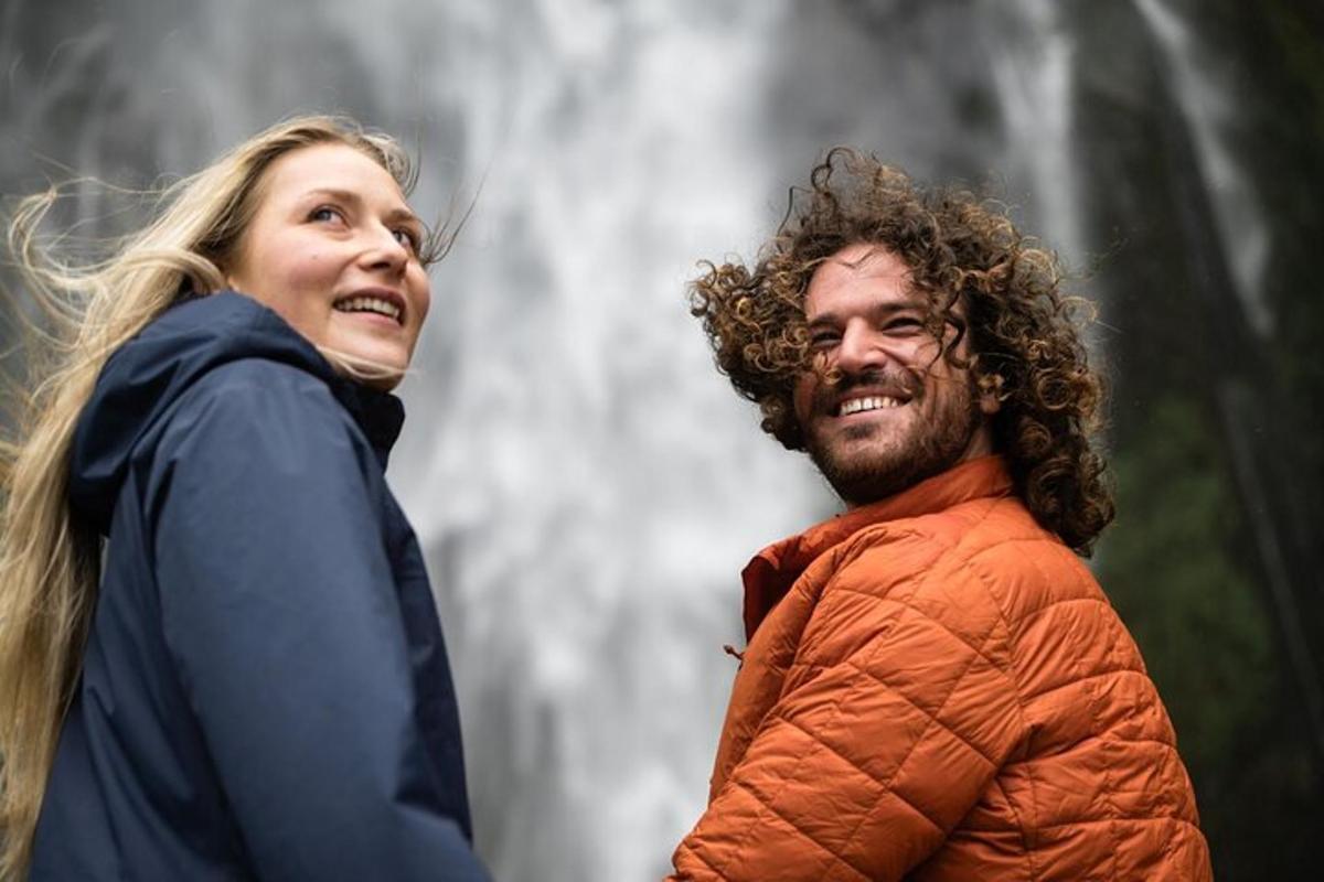a man and a woman standing in front of a waterfall