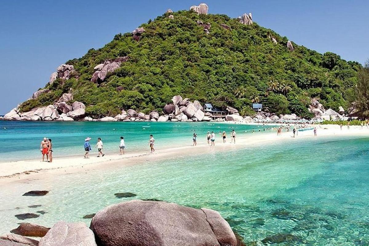 eine Gruppe von Menschen, die an einem Strand mit einer Insel spazieren gehen