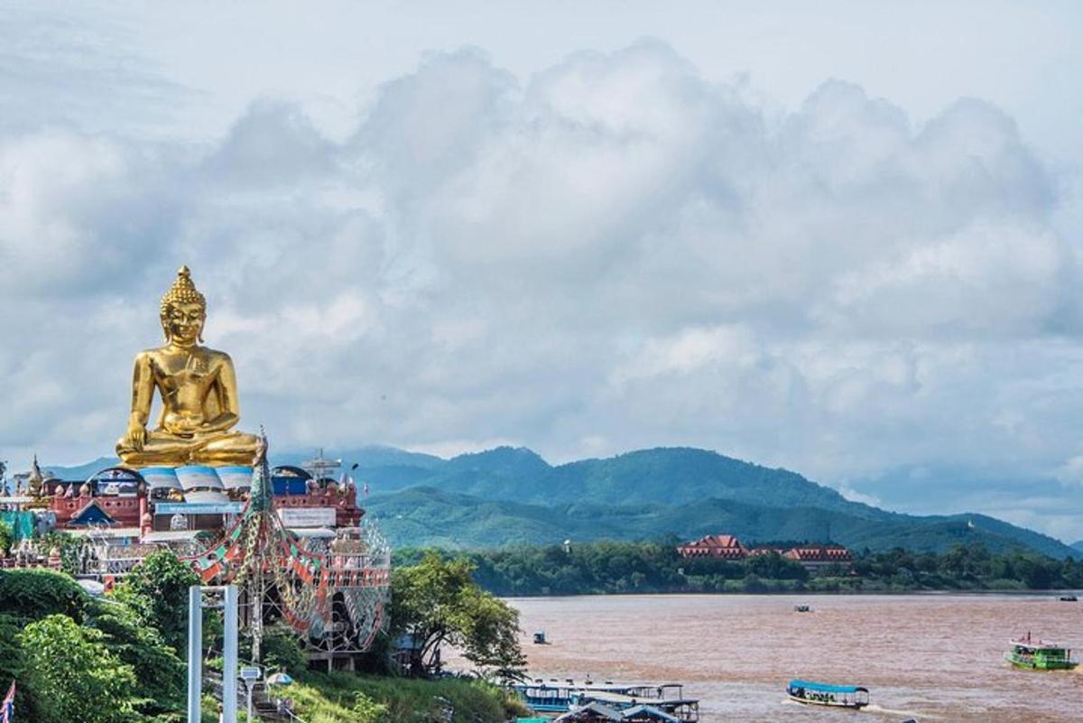 una grande statua dorata seduta sulla riva di un fiume