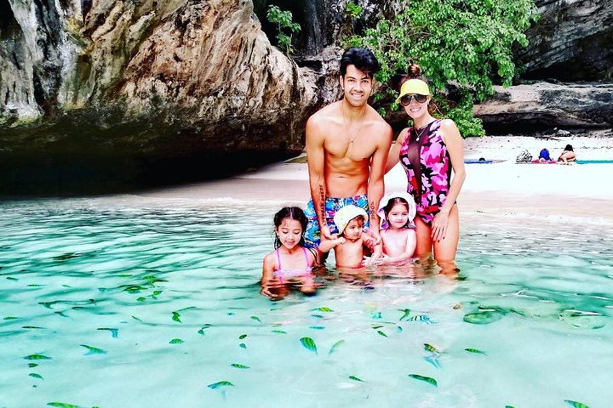 sebuah keluarga berdiri di dalam air di pantai