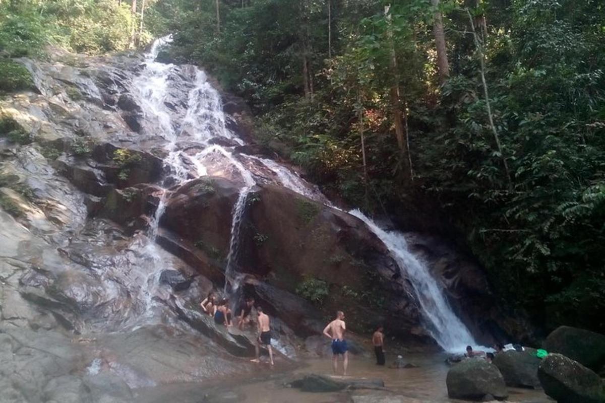 um grupo de pessoas em pé em frente a uma cachoeira
