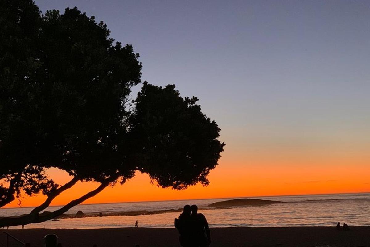 a couple sitting on the beach watching the sunset