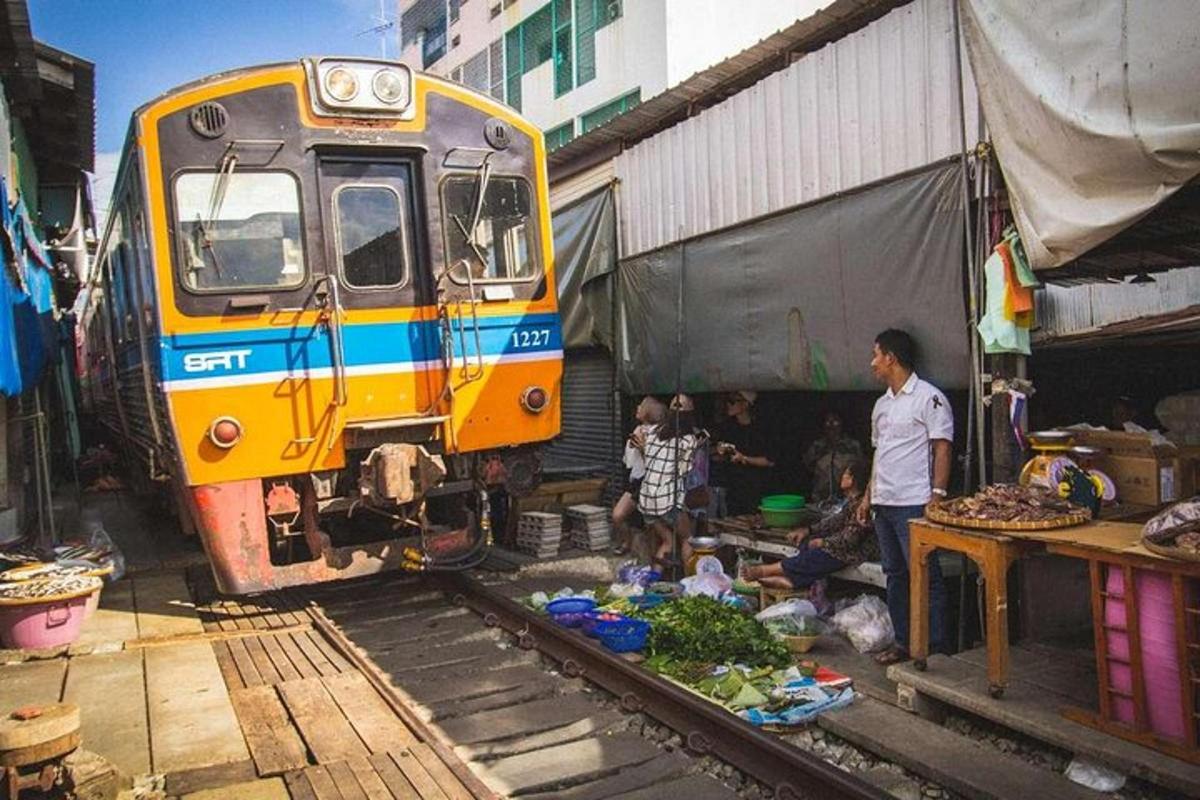 một đoàn tàu đang đỗ cạnh một khu chợ với một nhóm người