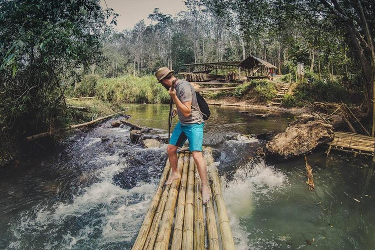 um homem em pé em uma ponte de bambu sobre um rio
