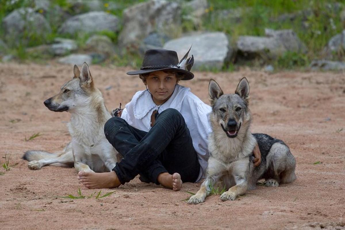 a man in a cowboy hat sitting next to two dogs