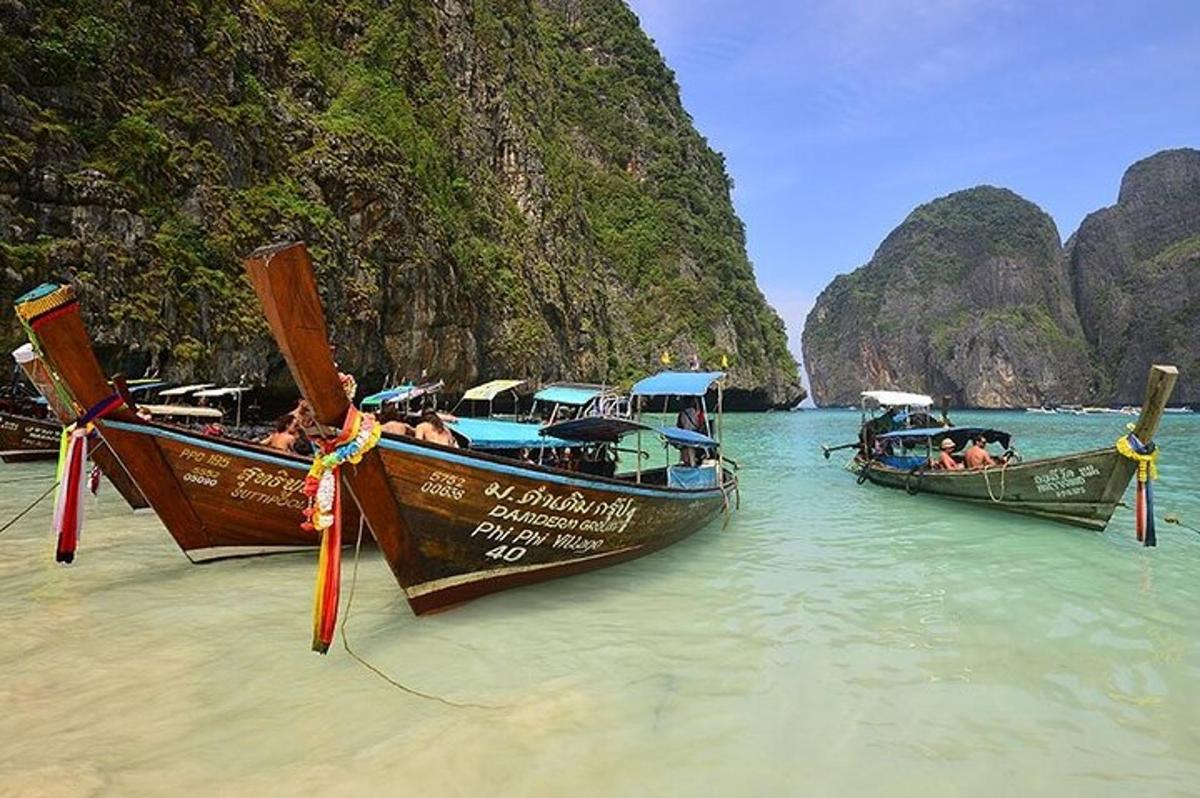 three boats in the water on a beach