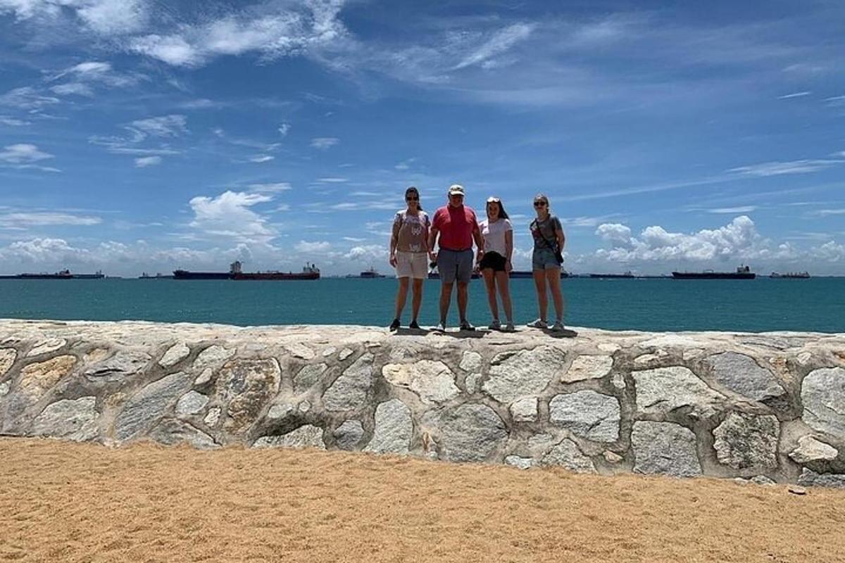 a group of people standing on a rock wall near the ocean
