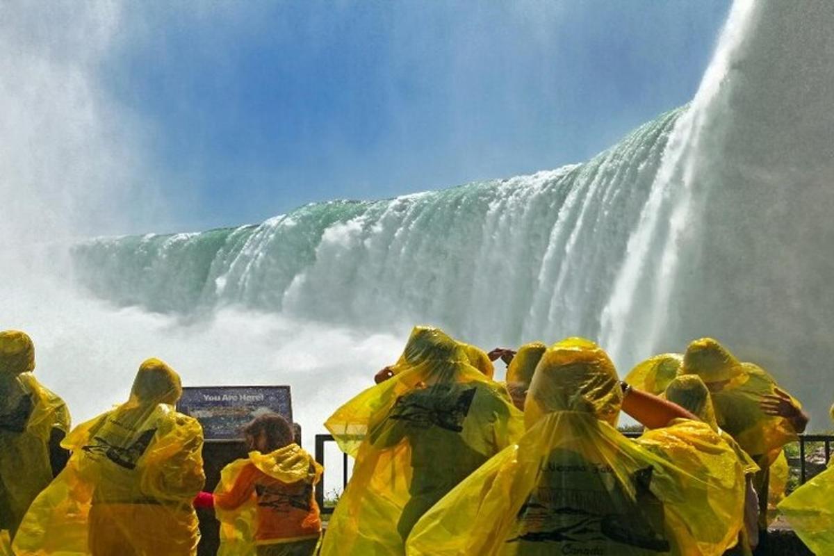 a group of people in yellow rain suits standing in front of a waterfall