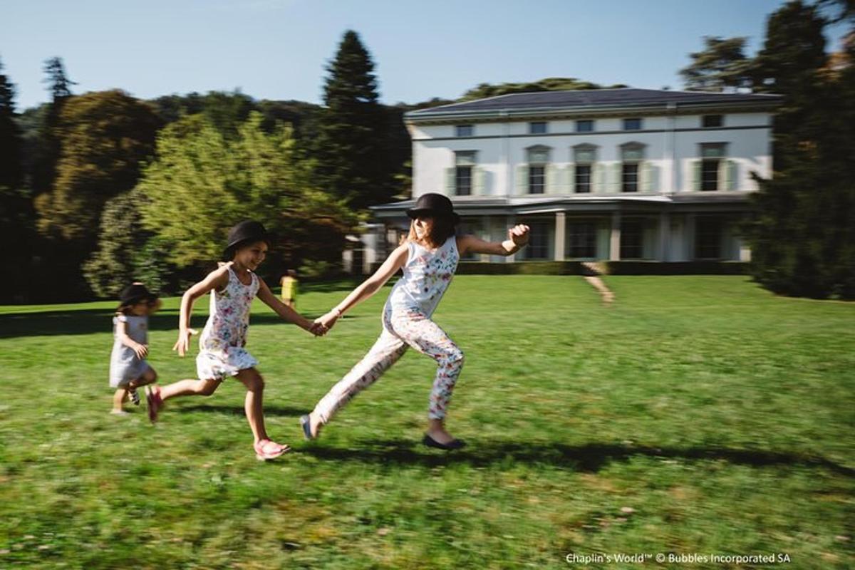 two girls are running in the grass in front of a house