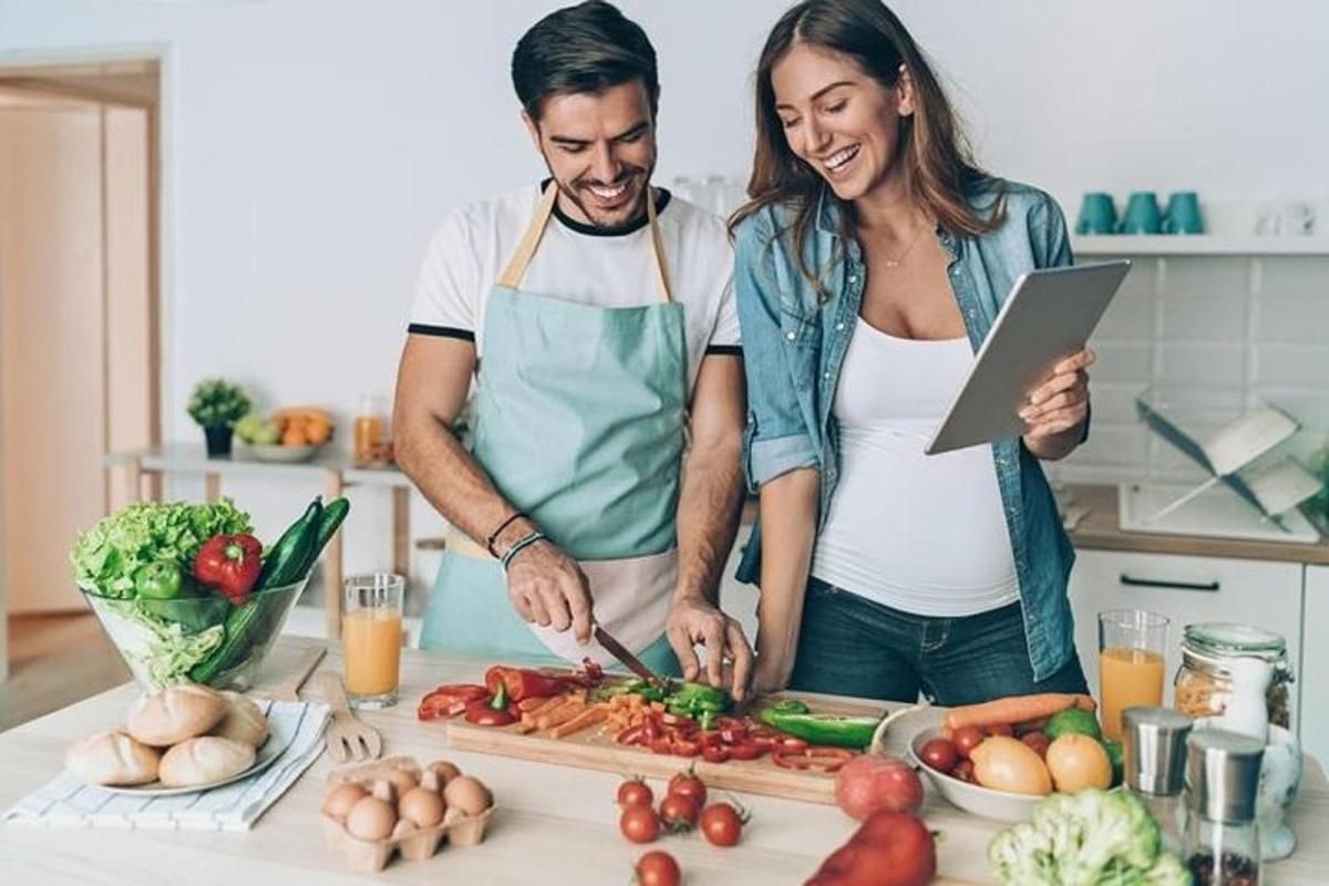 un uomo e una donna in piedi in cucina che tagliano le verdure