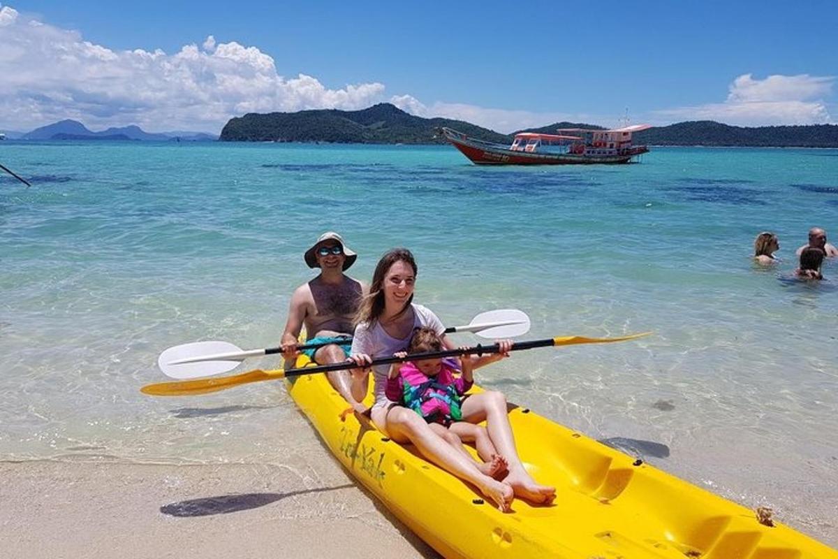 a family sitting in a kayak on the beach