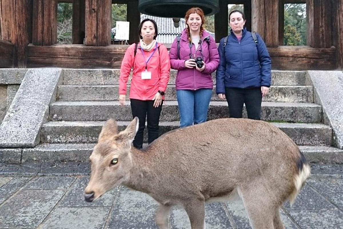 a group of three women standing next to a deer