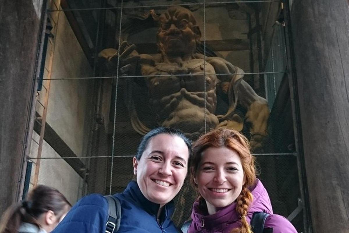two women standing in front of a statue