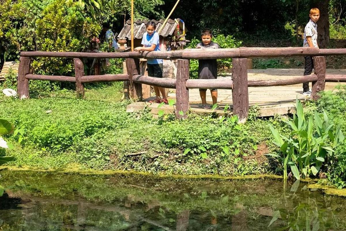 drei Kinder stehen auf einer Holzbrücke über einem Teich