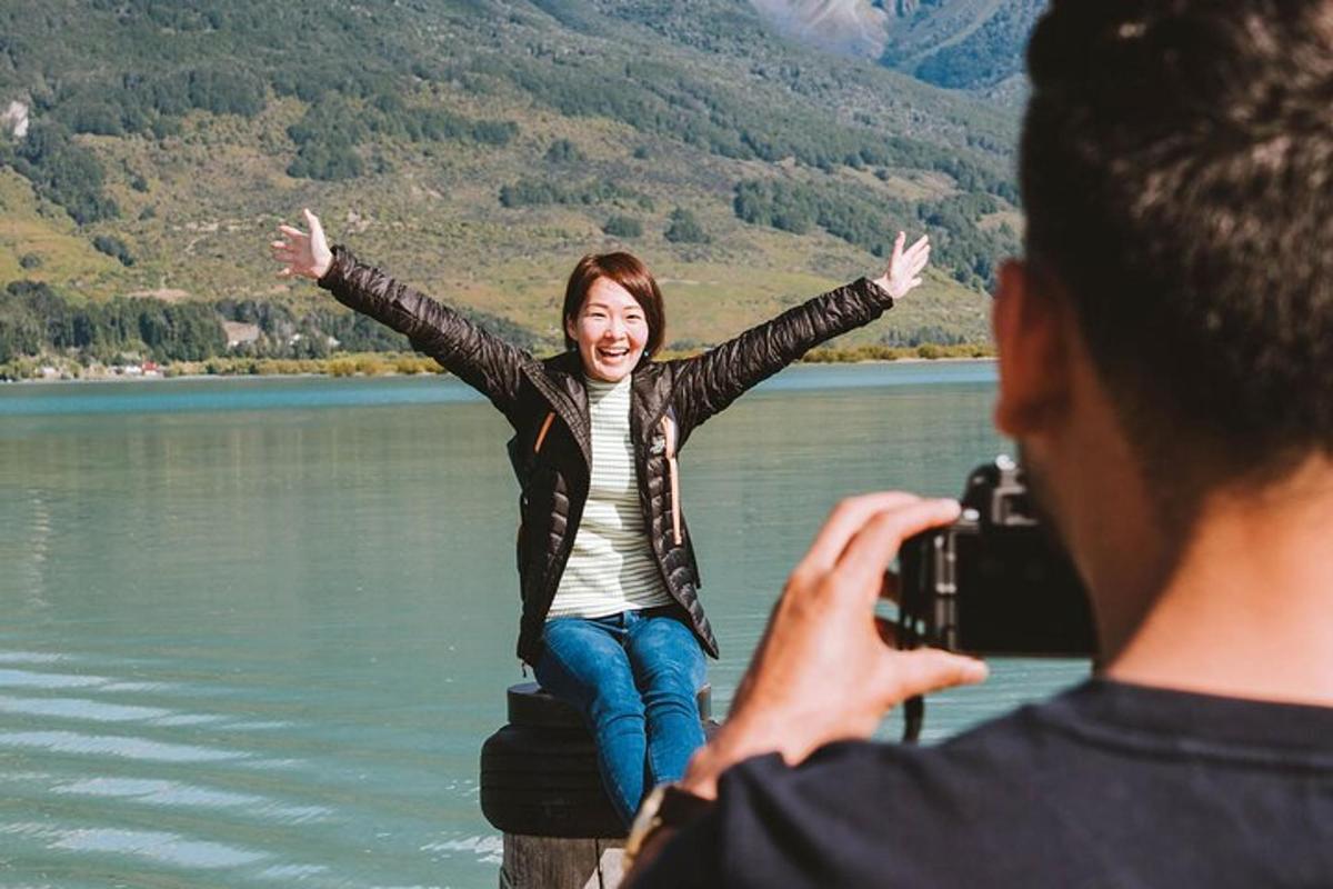 a man taking a picture of a woman sitting on a dock by a lake