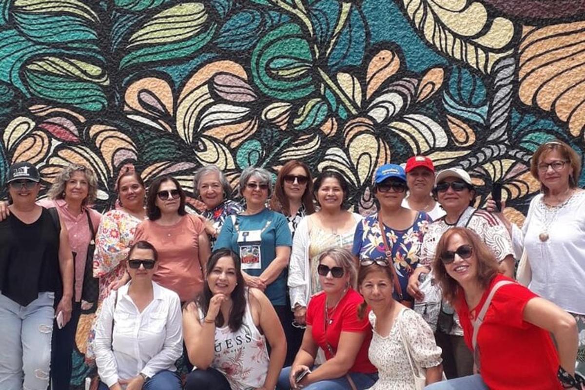 Un grupo de personas posando frente a un mural.