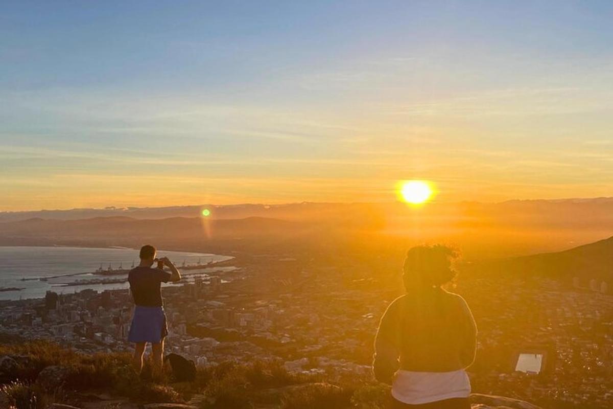to personer står på toppen af en bakke og kigger på solnedgangen