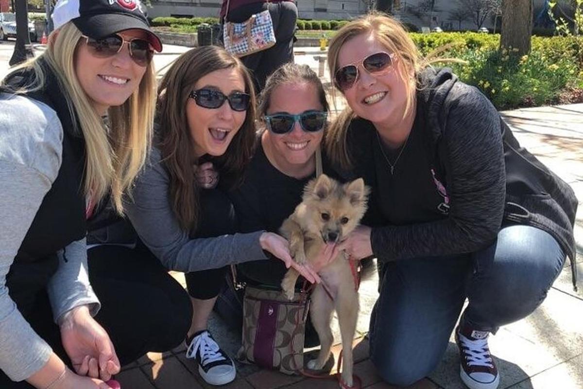 a group of women posing with a small dog
