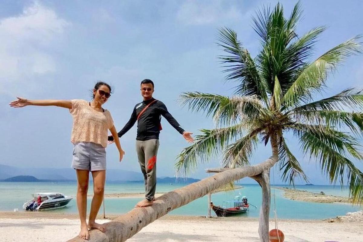 en mann og en kvinne som står på en tømmerstokk på en strand