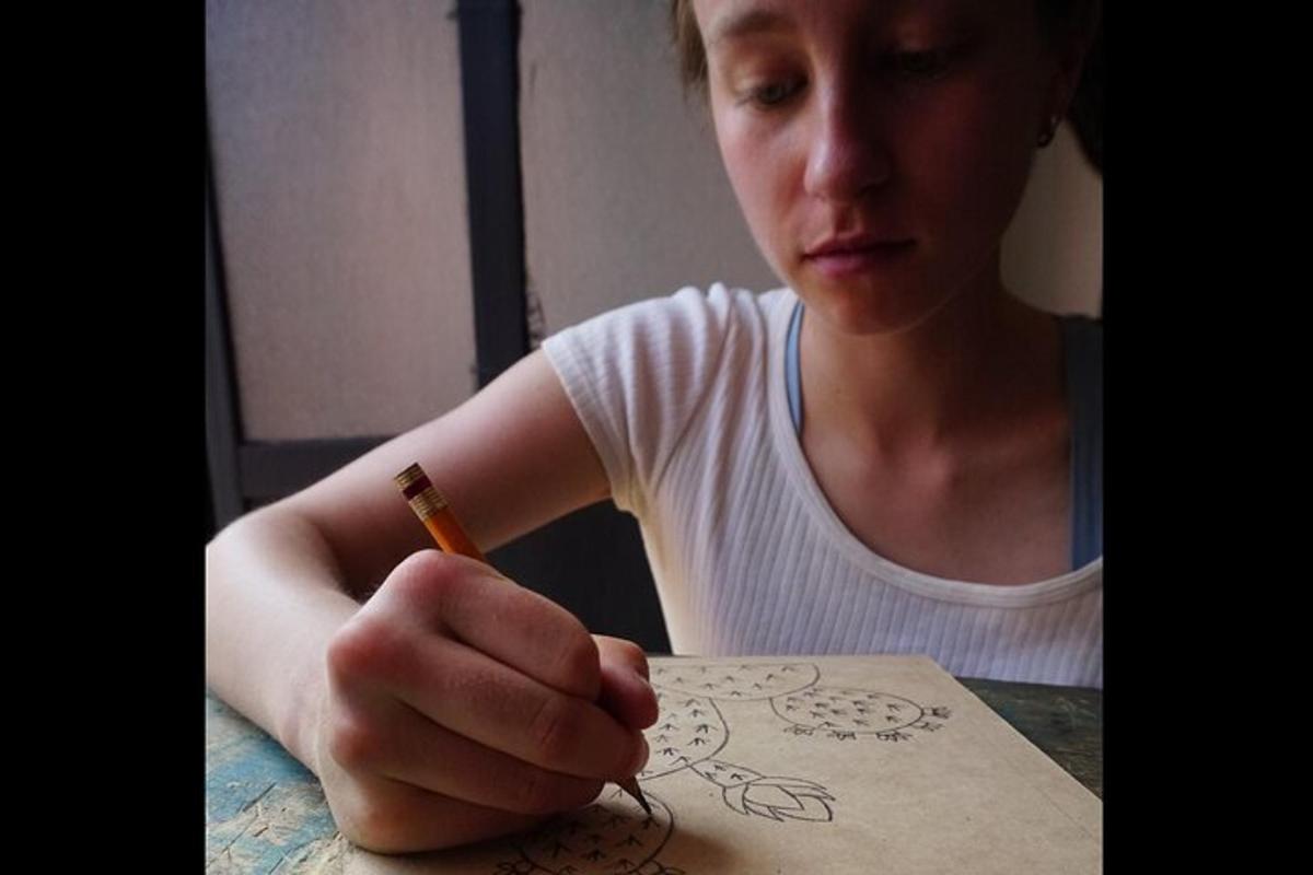 a woman sitting at a table holding a pencil