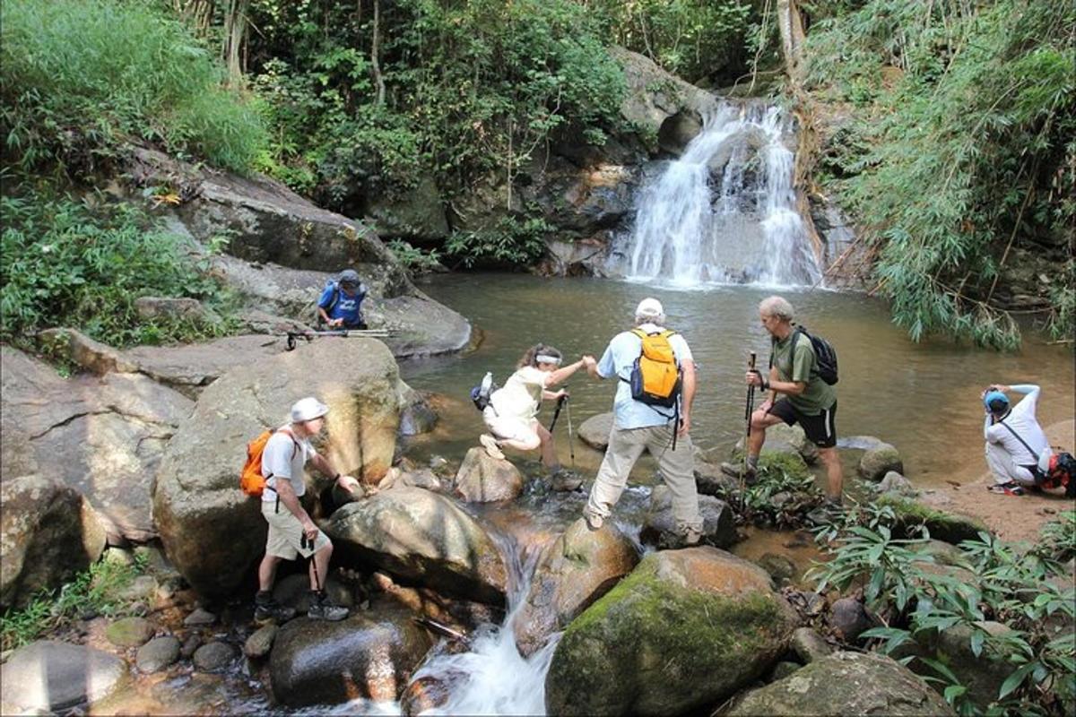 un gruppo di persone che attraversa un ruscello di fronte a una cascata