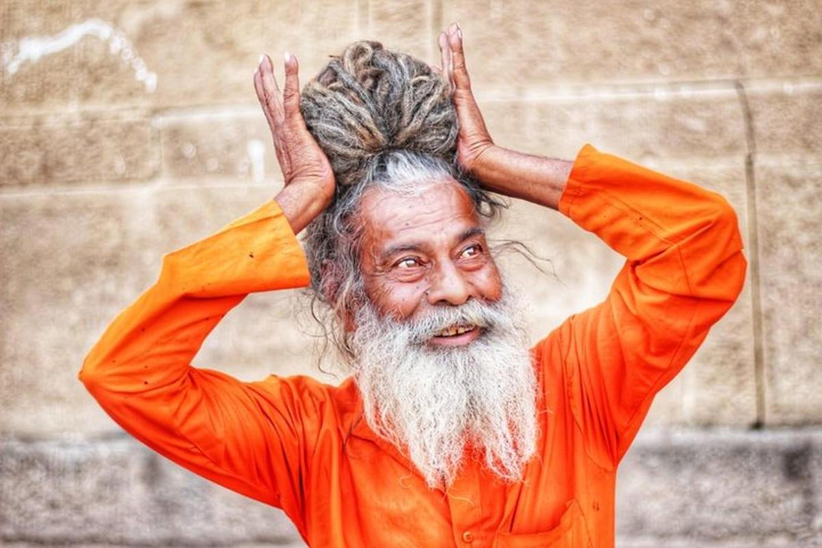 um homem mais velho com uma longa barba e uma camisa laranja