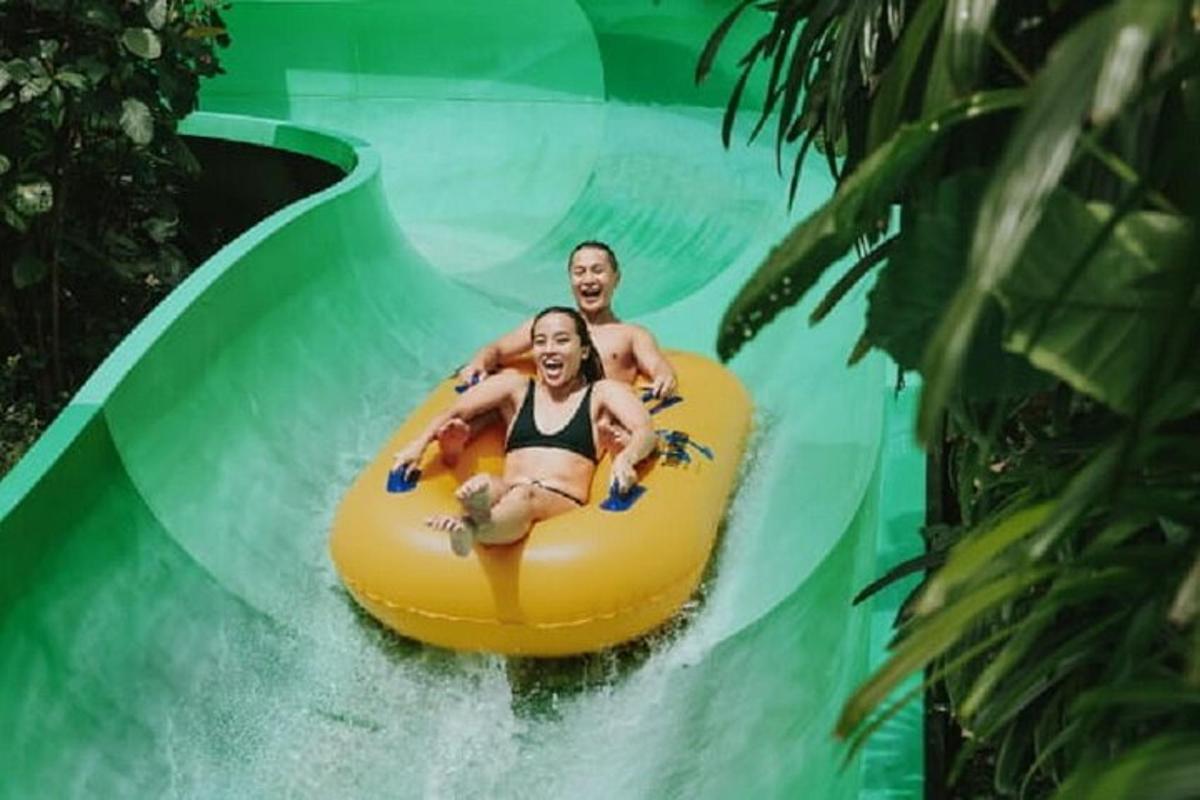 a man and a woman riding a raft down a fake wave