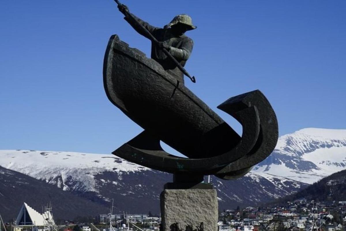 statuja, kurā attēlots vīrietis laivā pilsētā