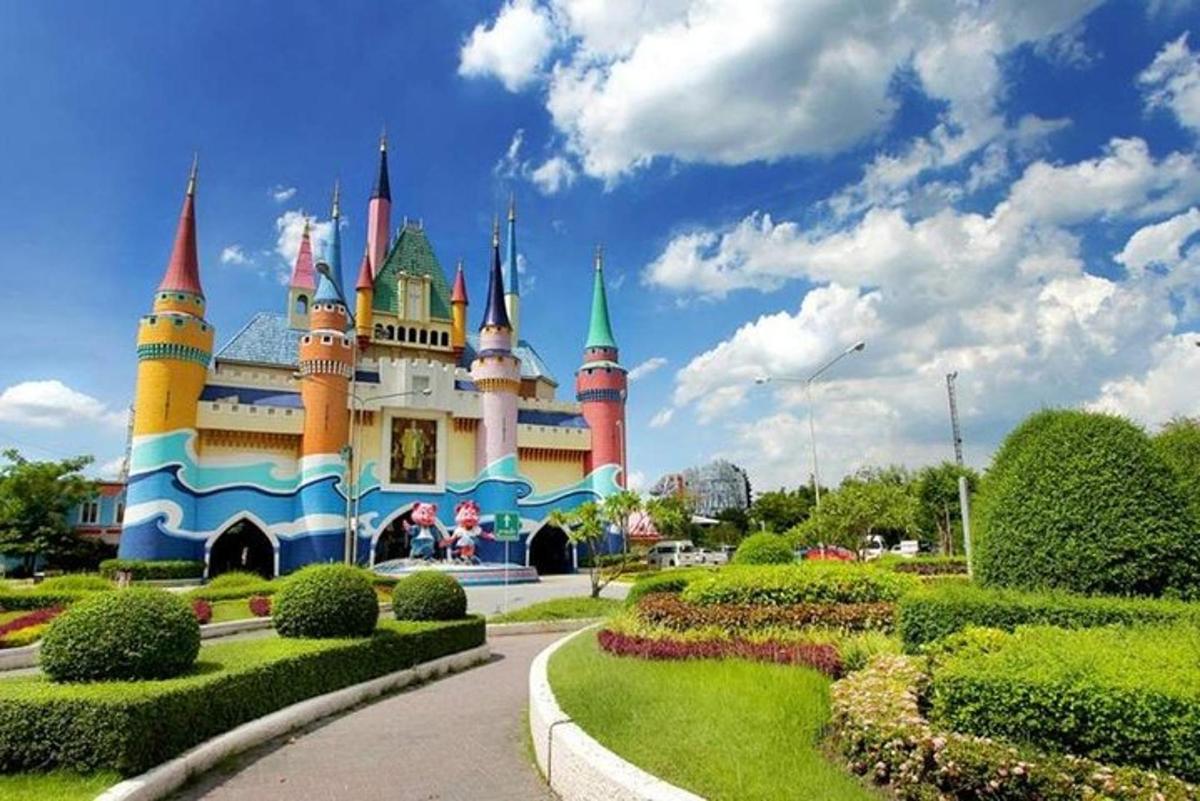 Un edificio de castillo de Disney con un jardín delante.