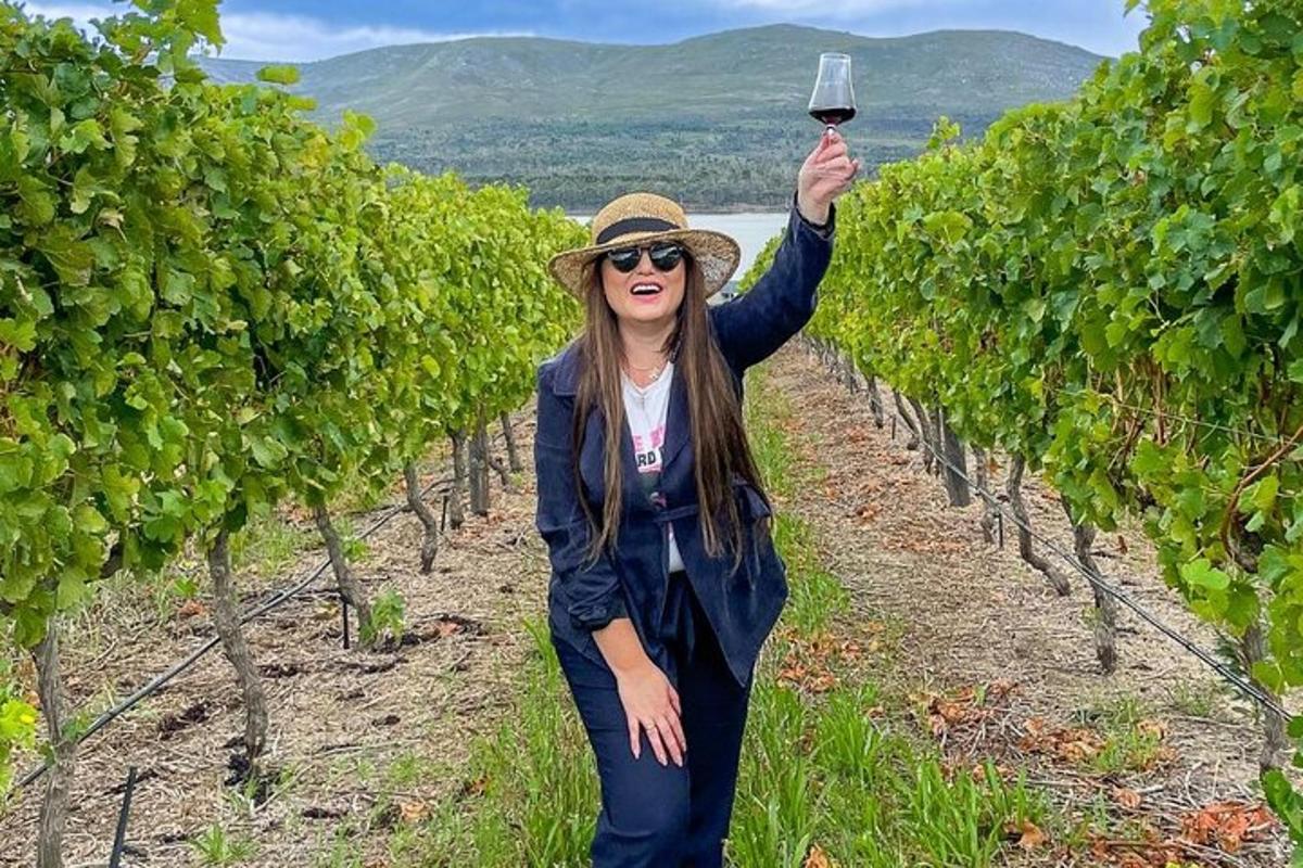 una donna che regge un bicchiere di vino in un vigneto