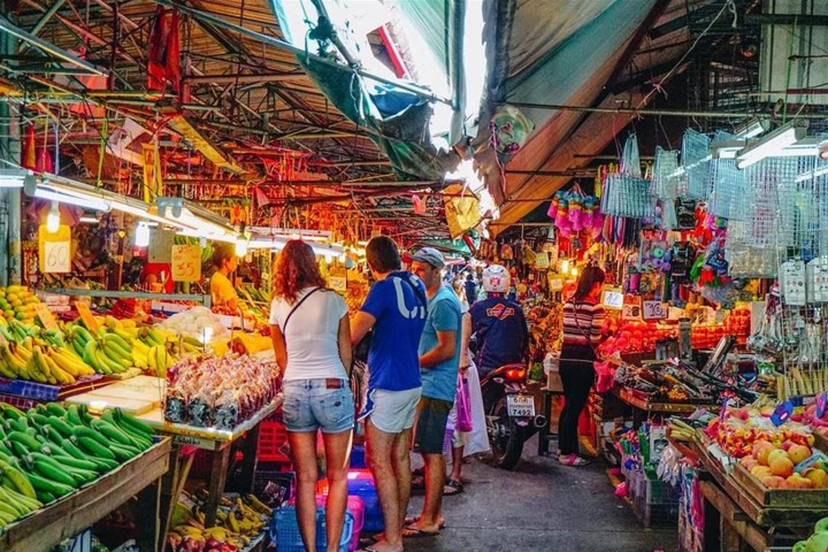 un gruppo di persone che camminano in un mercato di frutta e verdura