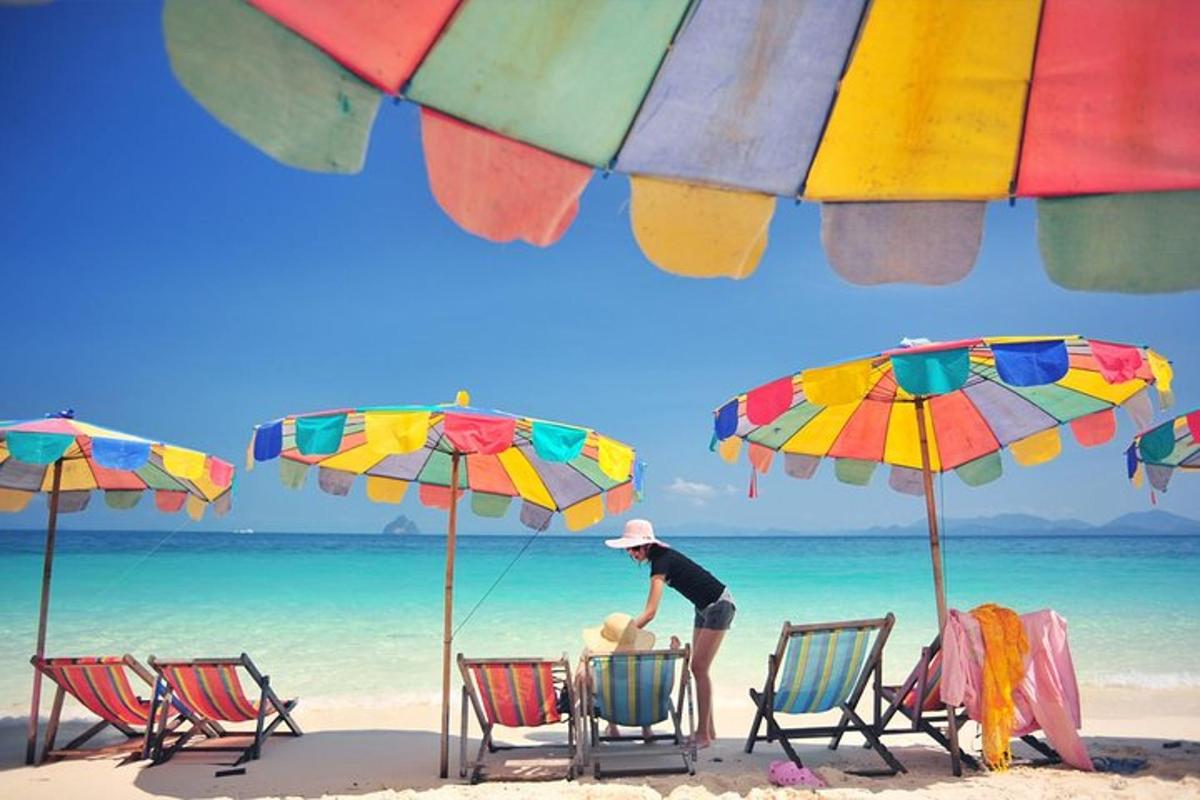 twee mensen zitten op stoelen op een strand met parasols