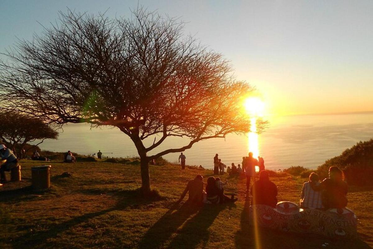un gruppo di persone sedute su una collina a guardare il tramonto
