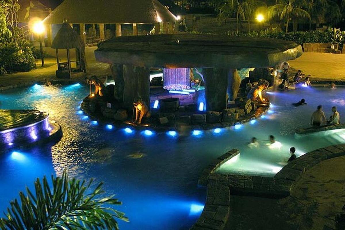 a pool with people swimming in it at night