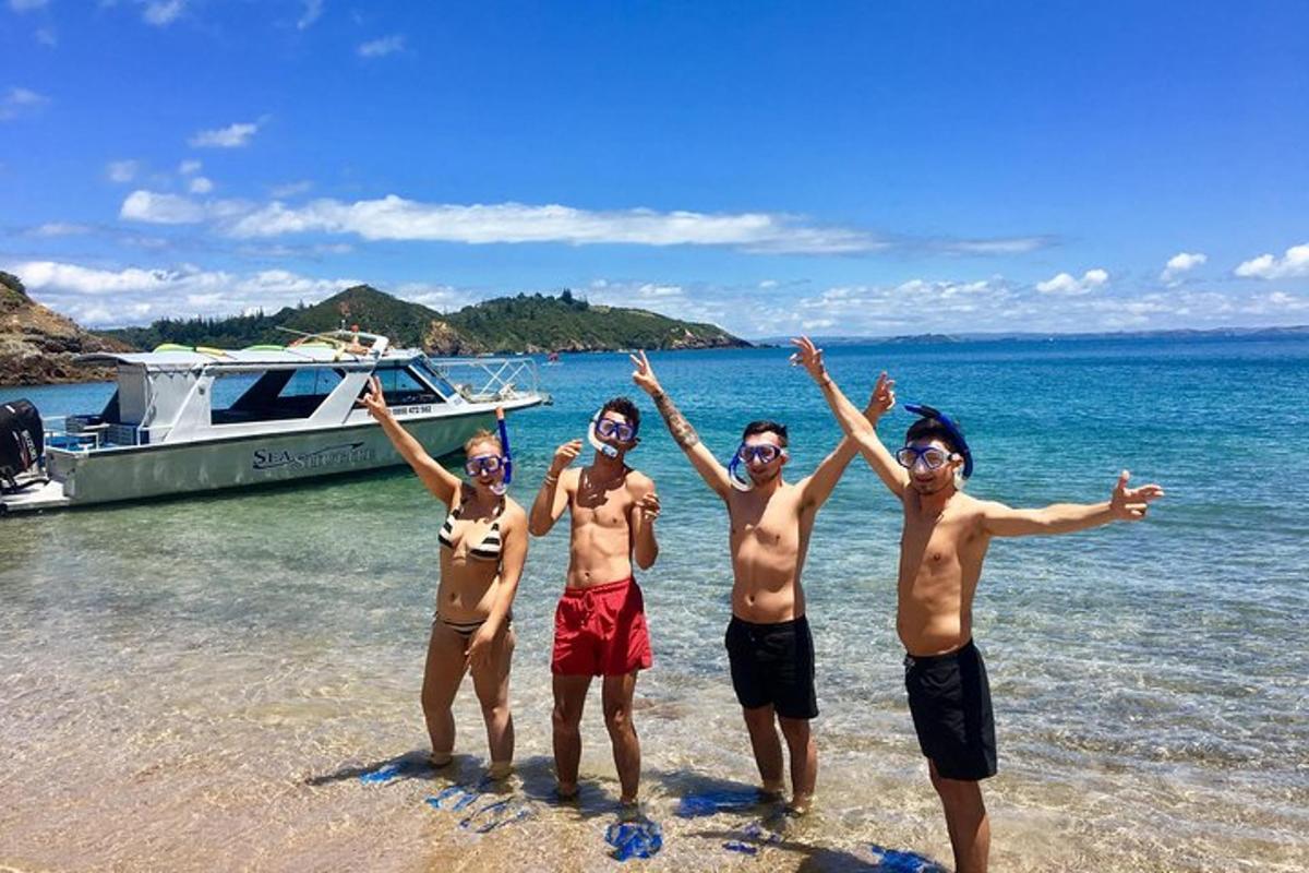 um grupo de meninos em pé na praia com um barco