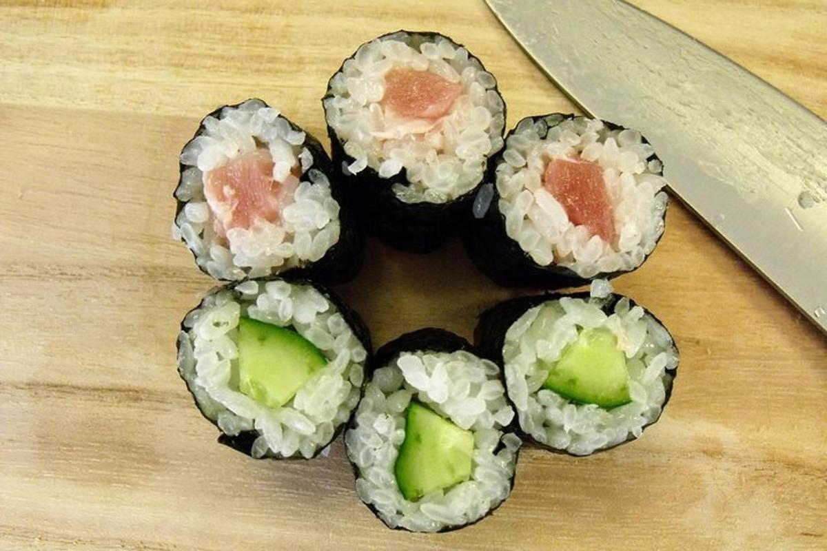 fjórar sushi-rúllur á skurðarbretti með hníf