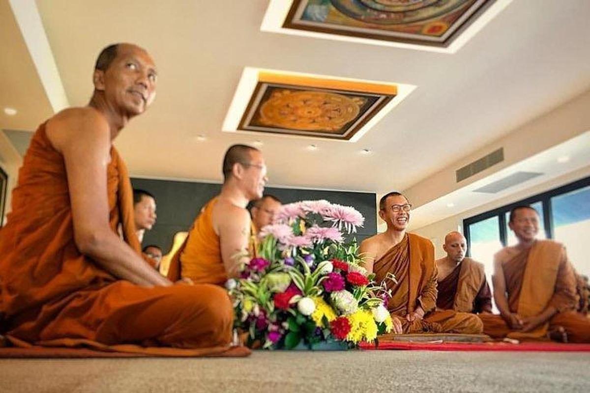 a group of monks sitting in a room with a bouquet of flowers