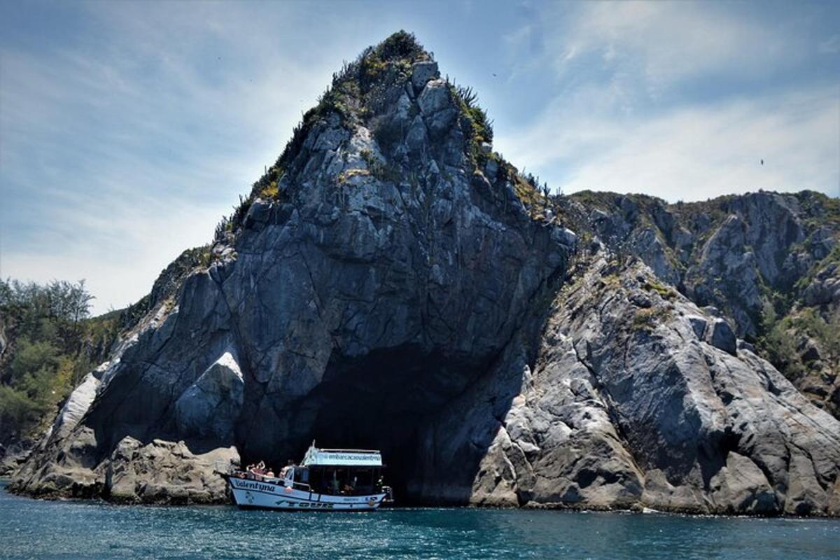 a boat in the water in front of a rock formation