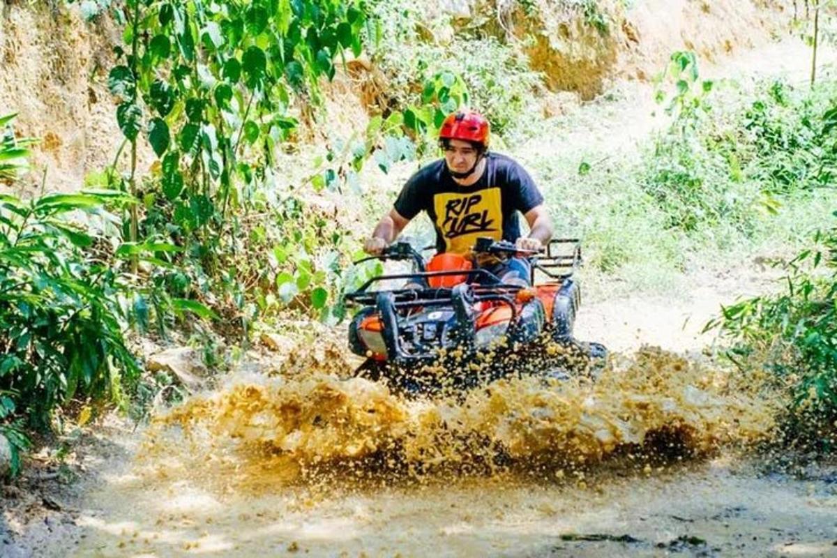 un home que condueix un quad per un camí fangós
