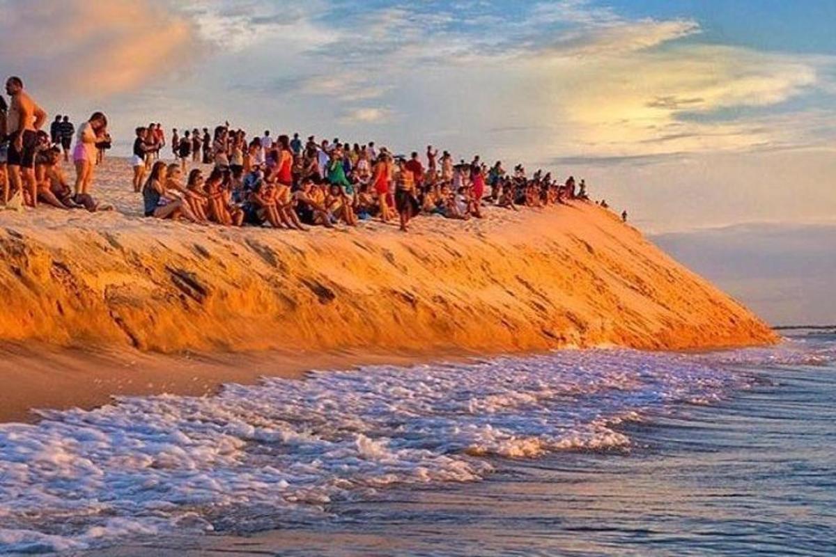 a group of people standing on a rock near the ocean