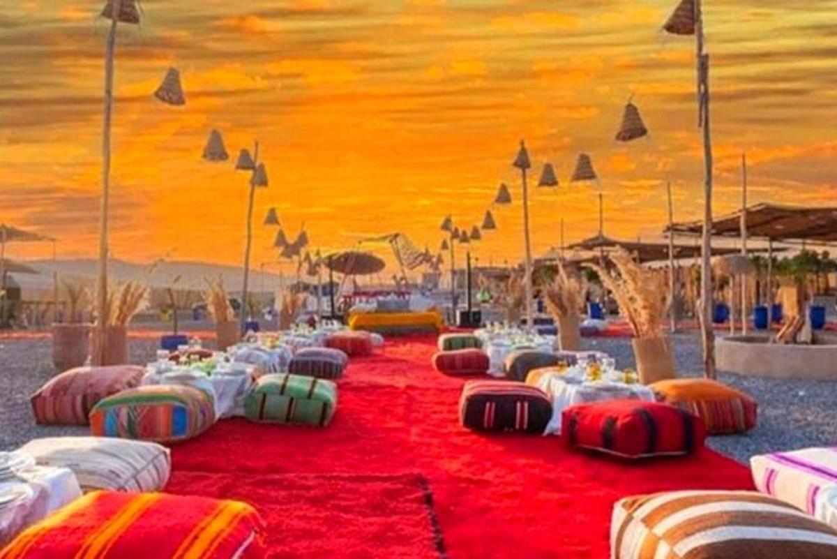 a group of tables on a beach with a sunset