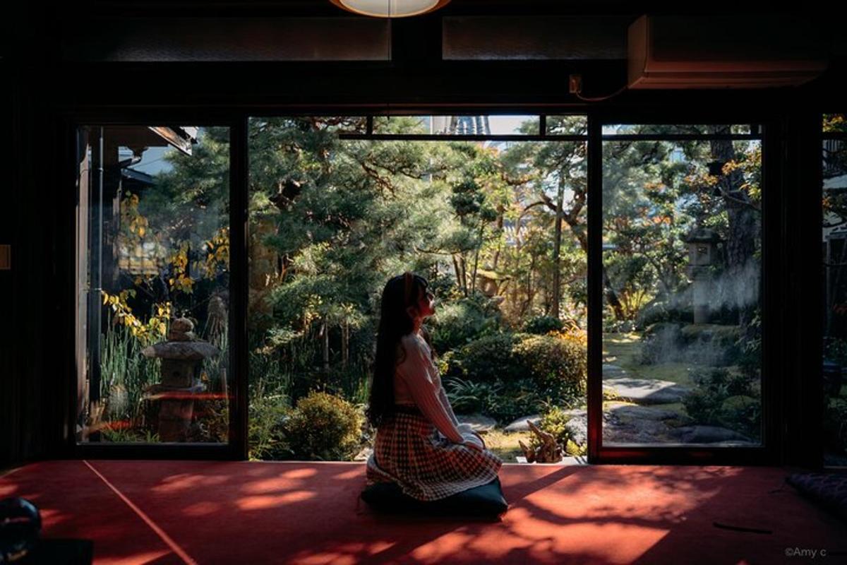 a woman sitting in front of a window looking at a garden